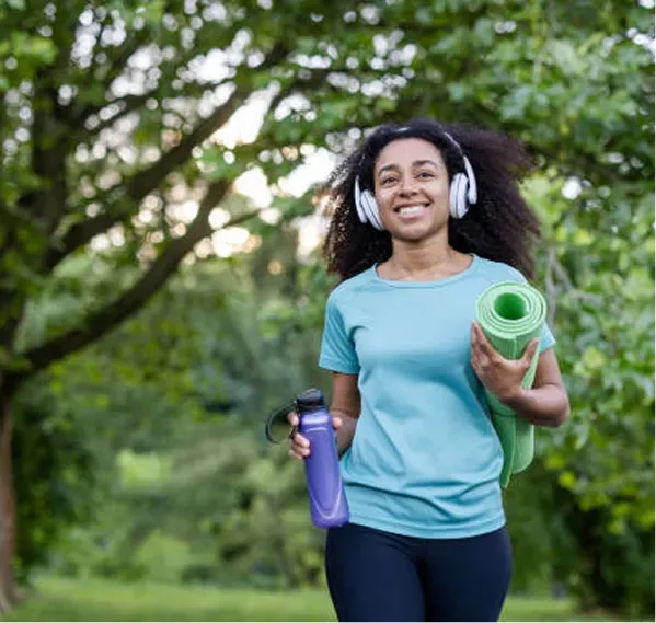 A woman with headphones and a yoga mat.